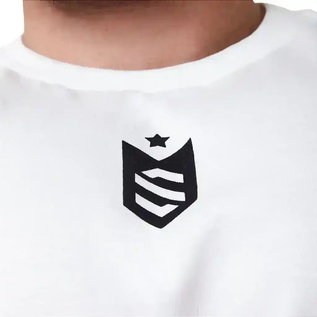 Detalhe de camiseta branca com estampa de brasão preto e estrela, moda fitness
