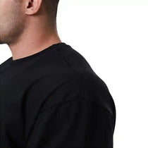 Homem vestindo camiseta preta de algodão, visto de perfil sobre fundo branco.