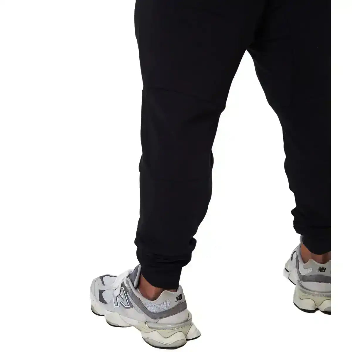 Calça esportiva preta masculina, vista traseira, com tênis branco New Balance