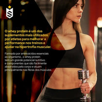 Mulher fit segurando haltere na academia, foco em treino, suplemento whey protein, hipertrofia muscular.