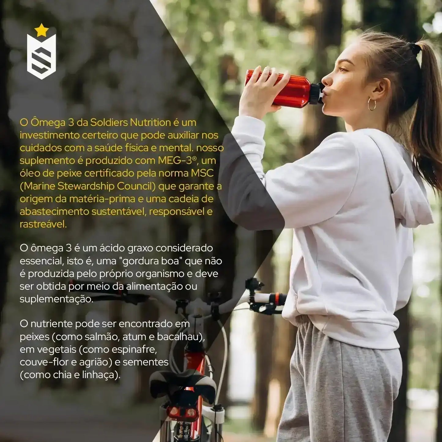 Jovem vestida de moletom cinza tomando suplemento energético com bicicleta ao fundo, ao ar livre.