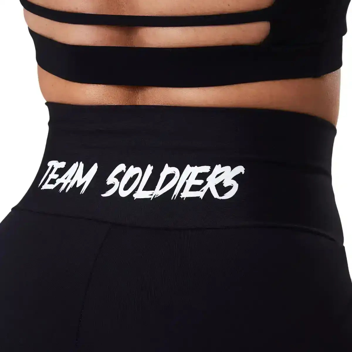 Detalhe de legging preta fitness com cós alto e estampa Team Soldiers em branco na cintura.